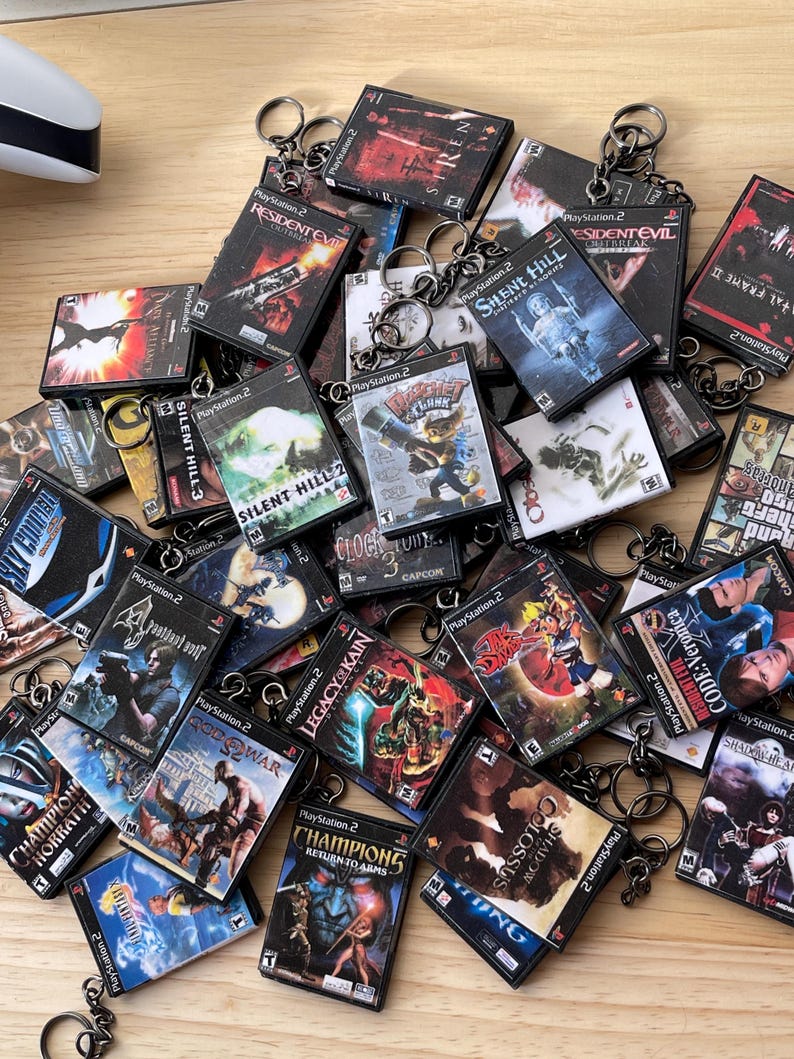 Puede incluir: Una colecci&oacute;n de llaveros de juegos de PlayStation 2 con varios t&iacute;tulos populares, incluyendo Resident Evil, Silent Hill y Clock Tower. Los llaveros est&aacute;n hechos de pl&aacute;stico negro y presentan la portada del juego.