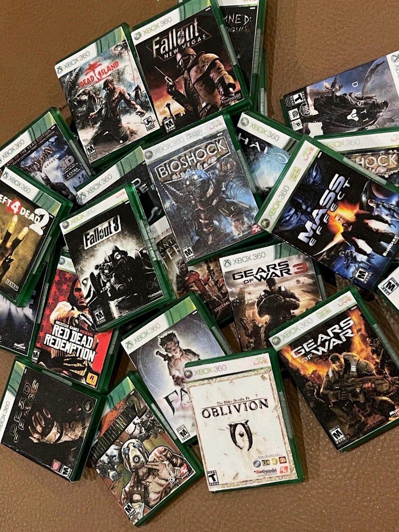 Puede incluir: Una colecci&oacute;n de cajas de juegos de Xbox 360, incluyendo t&iacute;tulos como Fallout 3, Gears of War, Red Dead Redemption y Oblivion. Las cajas son verdes y presentan varios personajes y logotipos de juegos.