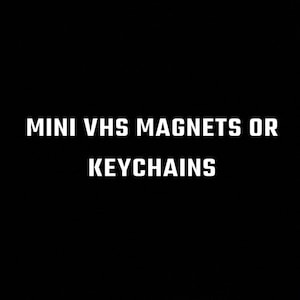 May include: Black and white text on a black background that reads "MINI VHS MAGNETS OR KEYCHAINS".