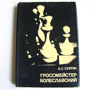 Può includere: Una copertina di libro vintage con sfondo nero e un disegno di pezzi degli scacchi giallo chiaro. Il titolo del libro e il nome dell'autore sono in testo bianco. Il libro si intitola "GROSSMEISTER BOLESLAVSKY".