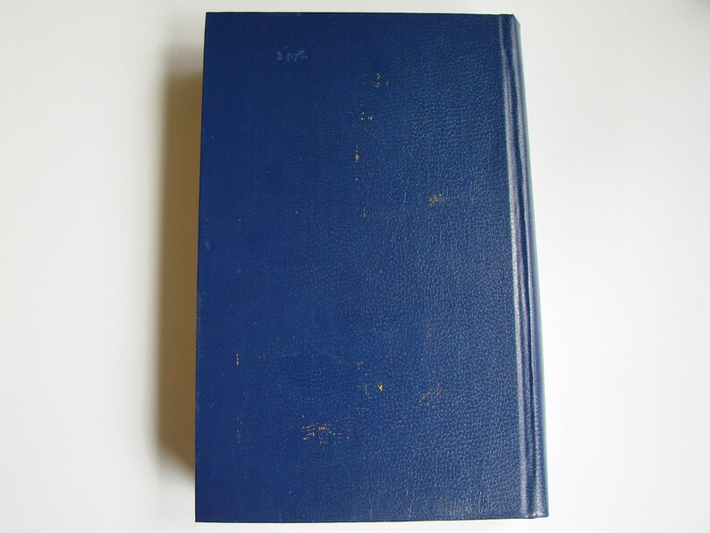 May include: A dark blue hardcover book with a smooth, textured cover. The book has a spine with gold lettering and a white label on the front cover.