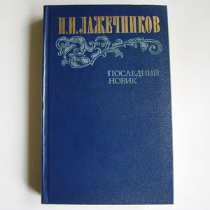 May include: A blue hardcover book with gold lettering on the spine and front cover. The title is "И.Н. ЛАЖЕЧНИКОВ" and "ПОСЛЕДНИЙ НОВИК".