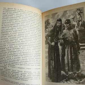 May include: Two men in long, dark robes stand together. The man on the left is wearing a black robe with a white collar and a long beard. The man on the right is wearing a dark brown robe with a white collar and a long beard. The man on the right has a white sash around his waist. The men are standing in front of a building with a white door.