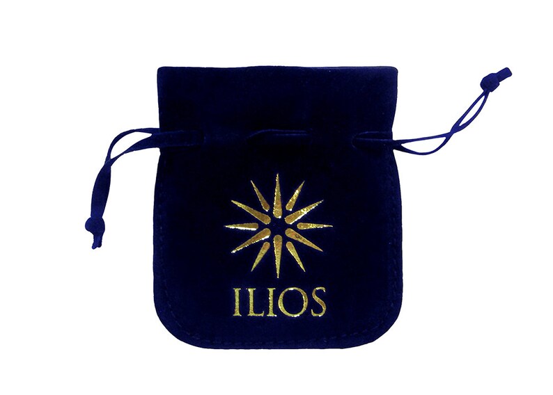 May include: A dark blue velvet pouch with a gold drawstring and a gold starburst logo with the word "ILIOS" printed below it.