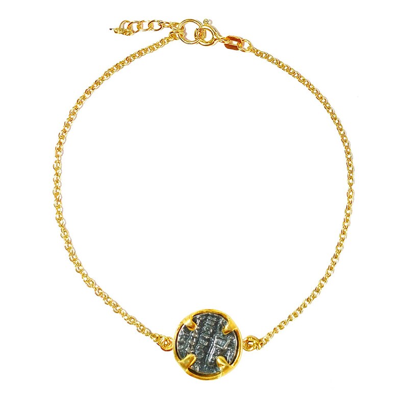 May include: A gold chain bracelet with a silver coin charm. The coin has a detailed design and is set in a gold bezel.