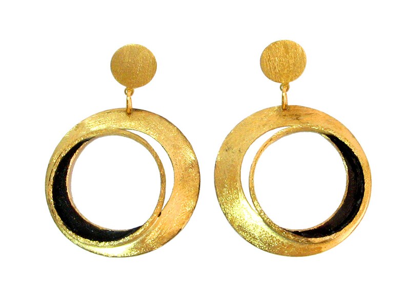 May include: A pair of gold-colored hoop earrings with a circular design. Each earring features a small, round stud at the top and a larger, textured hoop with a black inner section. The earrings are displayed against a white background.