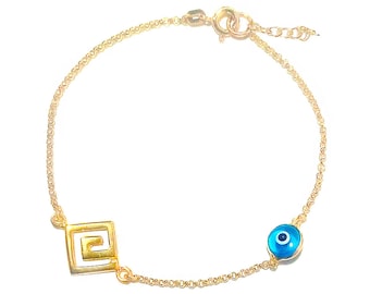May include: A gold chain bracelet with a blue evil eye charm and a gold Greek key charm.