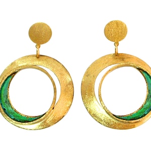 May include: A pair of gold-toned hoop earrings with a textured finish. Each earring features a large, open circle design with a smaller, curved inner shape, accented with green enamel. A small, round stud tops each earring.