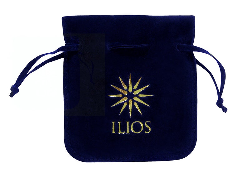 May include: A navy blue velvet drawstring pouch with a gold sunburst design and the word "ILIOS" printed below. The pouch has a soft texture and a drawstring closure.