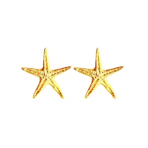 Op de afbeelding: Een paar gouden zeesterren oorbellen. De oorbellen zijn klein en delicaat en hebben een getextureerd oppervlak.