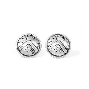 Puede incluir: Un par de pendientes de botón de plata con un diseño circular y una forma de escudo texturizada en relieve. El escudo tiene un diseño en forma de V puntiagudo en relieve en el centro.