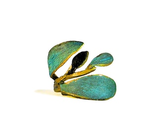 May include: A turquoise and gold ring with a leaf design. The ring is made of metal and has a textured finish.