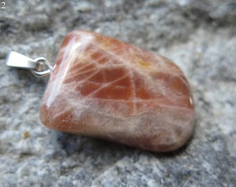 May include: A pendant featuring a sunstone with a reddish-brown and white color pattern. The stone is attached to a silver chain.
