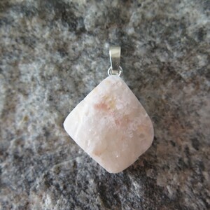 May include: A white and pink gemstone pendant with a silver bail. The pendant is shaped like a diamond and has a rough, textured surface.