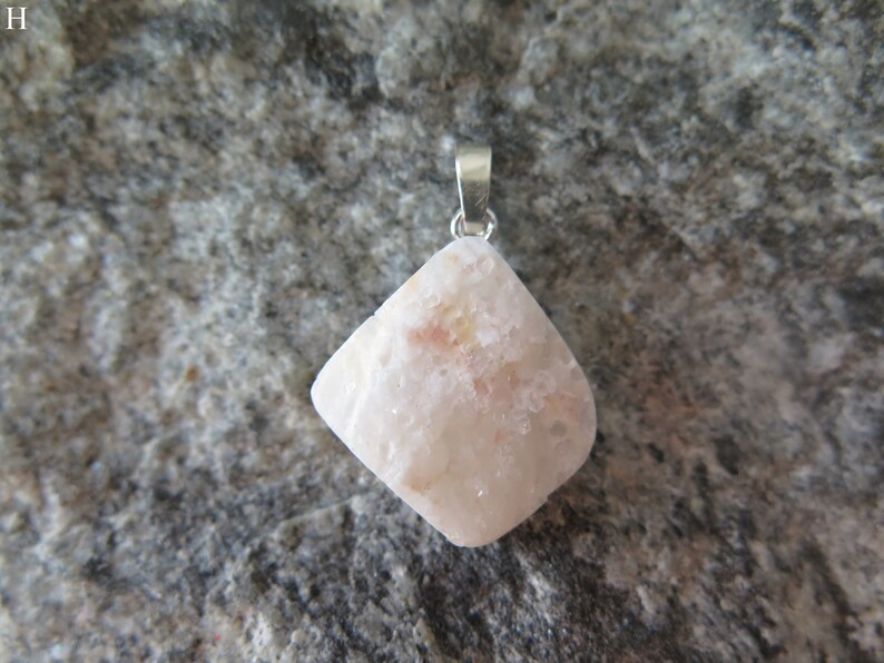 May include: A white and pink gemstone pendant with a silver bail. The pendant is shaped like a diamond and has a rough, textured surface.