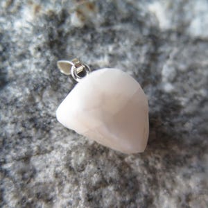 May include: A white, irregularly shaped pendant with a silver bail. The pendant is made of a smooth, opaque material.
