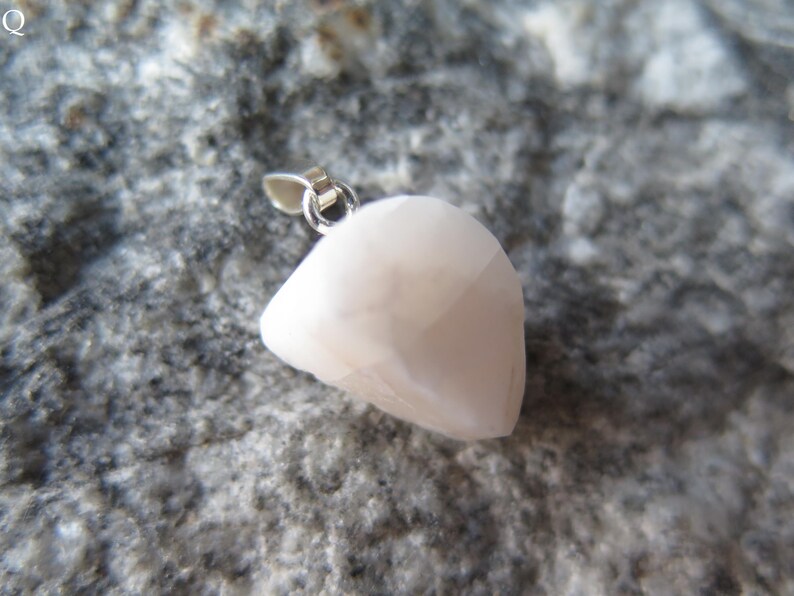 May include: A white, irregularly shaped pendant with a silver bail. The pendant is made of a smooth, opaque material.
