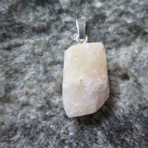 May include: A white crystal pendant with a silver bail. The crystal is rough and has a natural, unpolished look.