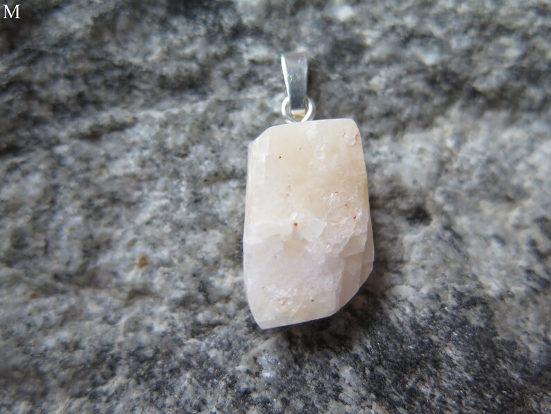 May include: A white crystal pendant with a silver bail. The crystal is rough and has a natural, unpolished look.