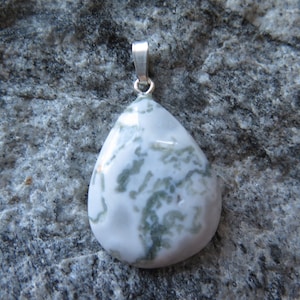 Può includere: Un ciondolo a forma di lacrima realizzato in agata muschiata bianca e verde con un'anellina in argento.