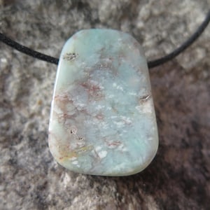 May include: A light blue and white pendant with a marbled pattern, hanging from a black cord.