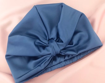 May include: A blue satin hair wrap with a bow on top. The wrap is designed to protect hair from damage while sleeping.