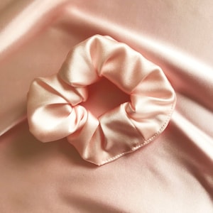 Puede incluir: Un scrunchie de satén rosa suave para el cabello.