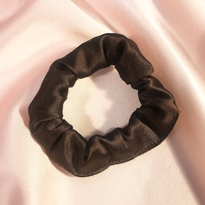 May include: A brown satin scrunchie for hair.