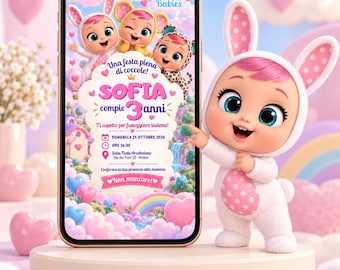 May include: A smartphone displaying a digital birthday invitation for Sofia's 3rd birthday, featuring Cry Babies characters, pink hearts, and rainbows. Next to the phone stands a small doll wearing a white and pink polka-dot bunny costume.
