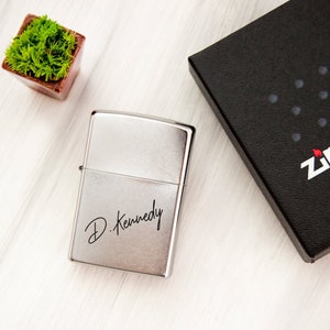 May include: Silver Zippo lighter with a personalized inscription that reads "D. Kennedy".