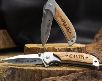 May include: Two pocket knives with wooden handles. The top knife has the name "OLIVE" engraved on the handle and the bottom knife has the name "CAVIN" engraved on the handle. Both knives have the words "Always with you" engraved on the blade.