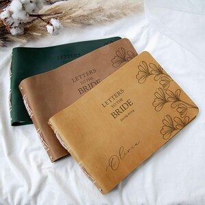 May include: Three leather-bound journals with the text "Letters to the Bride" and a floral design. The date "10.09.2024" and the name "Olivia" are also engraved on the journals.