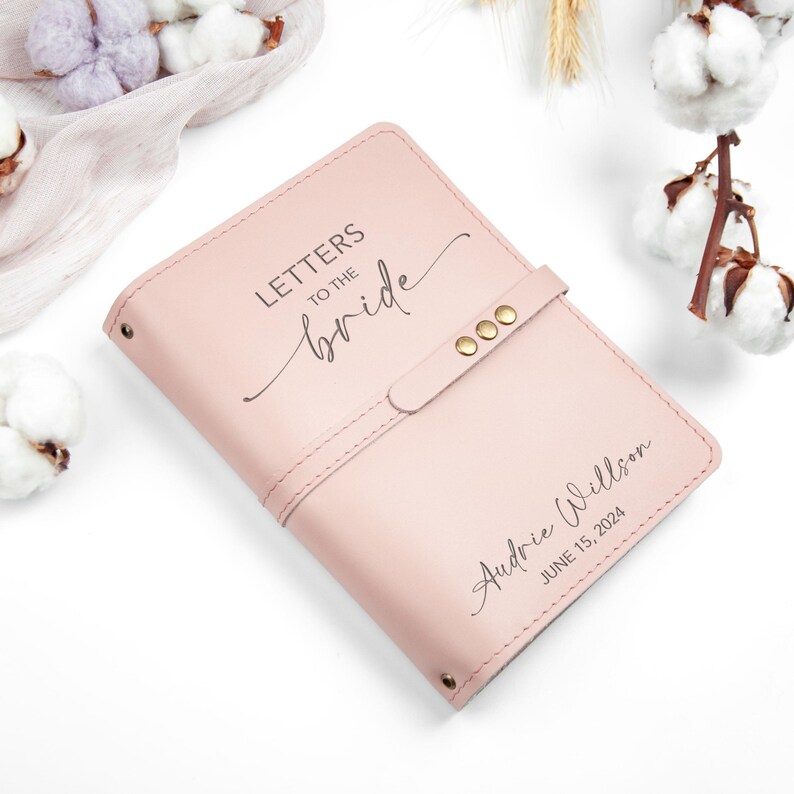 Op de afbeelding: Een roze lederen gebonden dagboek met de tekst "Brieven aan de bruid" en een gepersonaliseerde inscriptie die luidt "Audrie Willson 15 juni 2024".