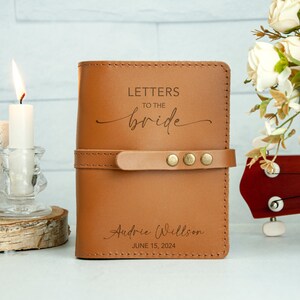Op de afbeelding: Een bruin lederen dagboek met de tekst "Letters to the bride" en "Audrie Willson June 15, 2024" gegraveerd op de voorkant.