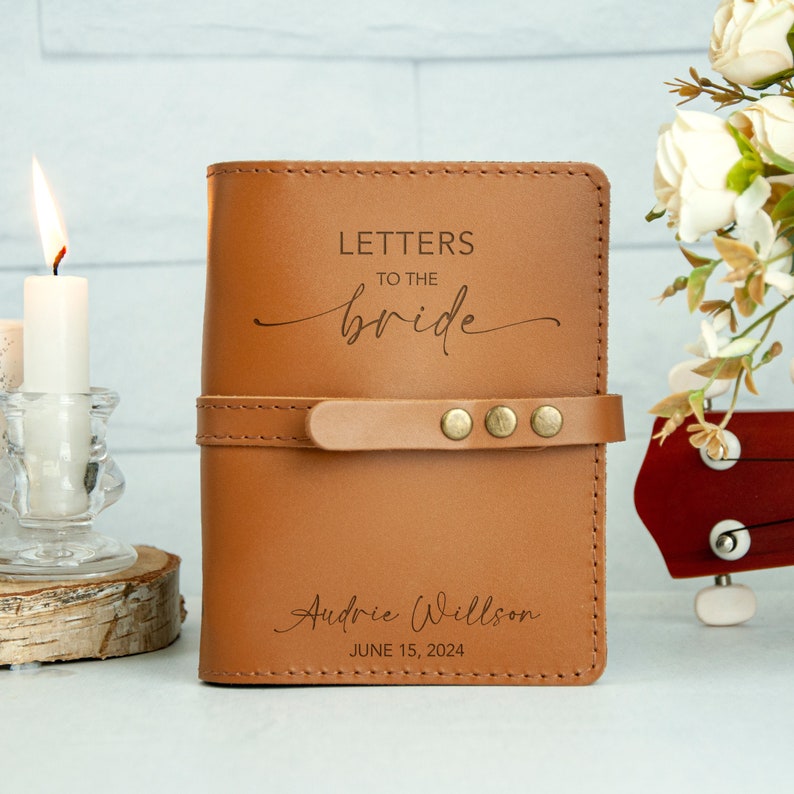 Op de afbeelding: Een bruin lederen dagboek met de tekst "Letters to the bride" en "Audrie Willson June 15, 2024" gegraveerd op de voorkant.