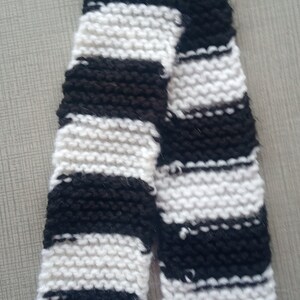 May include: A black and white striped knitted scarf. The scarf is made of a soft, fluffy yarn.