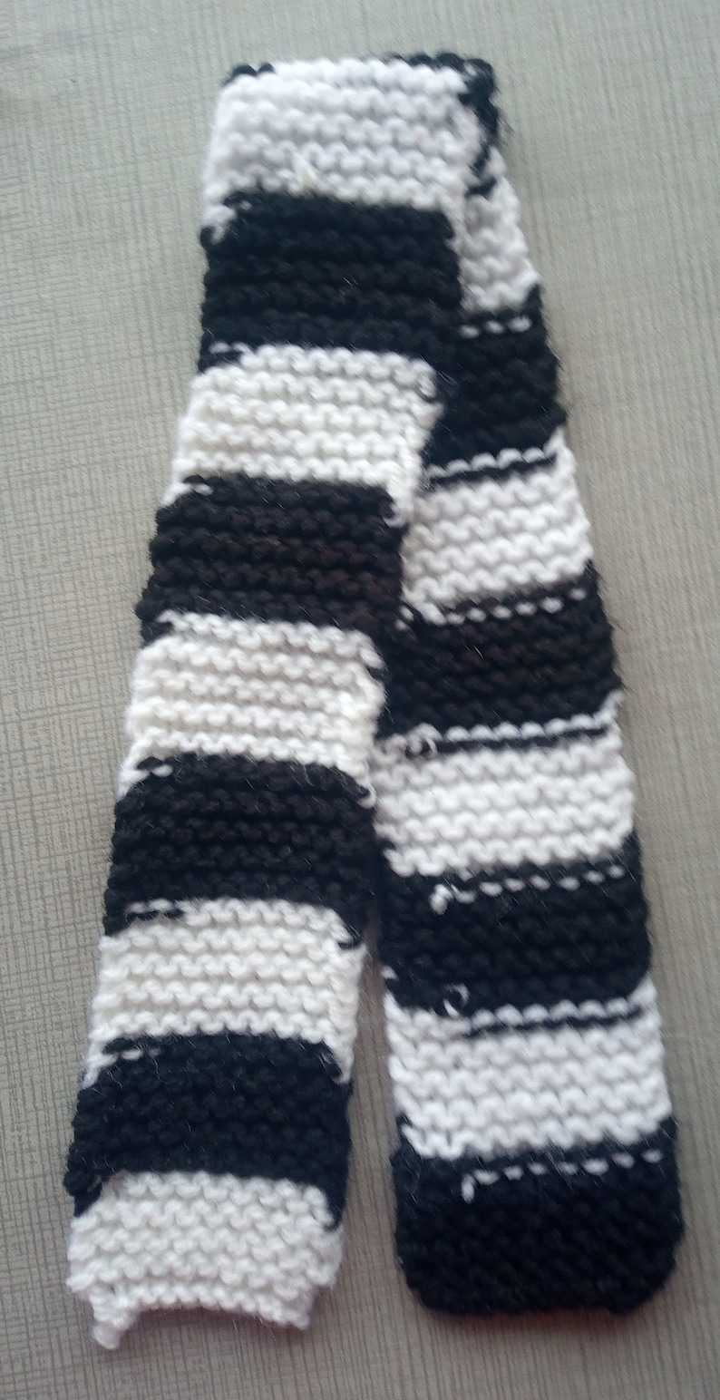 May include: A black and white striped knitted scarf. The scarf is made of a soft, fluffy yarn.