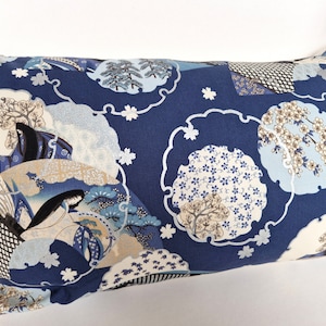 May include: Rectangular cushion featuring a navy blue fabric with a Japanese-inspired pattern. The design includes white, light blue, and beige circular motifs with cherry blossoms, figures, and clouds. A decorative home accessory.