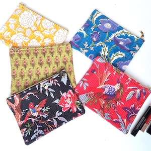 Peut inclure: Cinq pochettes rectangulaires à fermeture éclair avec divers motifs floraux et d'oiseaux en jaune, bleu, vert, noir et rouge. Le tissu présente une texture matelassée et chaque pochette possède une tirette dorée. Trois cosmétiques sont inclus.