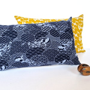 May include: Two decorative throw pillows, one with a blue and white wave pattern and the other with a yellow and white floral pattern.