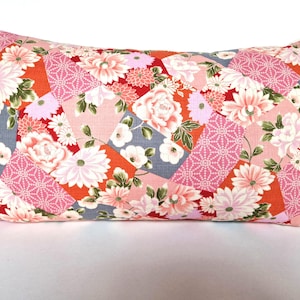 Peut inclure: Un coussin rectangulaire avec un motif patchwork composé de motifs floraux roses, rouges et gris. Le coussin est fait d'un tissu doux et texturé.