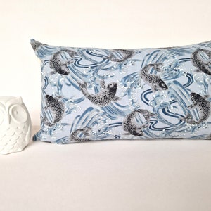 May include: A blue and white rectangular pillow with a pattern of black koi fish swimming in waves.