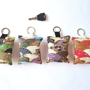 Sleutelhanger, tashanger van Japanse stof in diverse kleuren met goud, licht, sterk, zacht... in de vorm van kleine kussens, afm. 9 x 7 cm