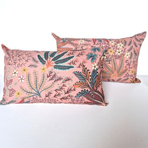 May include: Two pink cushion covers with a floral pattern featuring teal, orange, and brown accents.