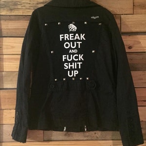 May include: Black denim jacket with silver studs and a white patch on the back that says "Freak Out and Fuck Shit Up".