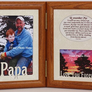 May include: A wooden picture frame with two openings. The left opening has a photo of a father and son, with the word "Papa" cut out of the frame. The right opening has a photo of a sunset with trees and the words "Love You Forever".
