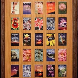 May include: A wooden picture frame with 25 openings for displaying photos or cards. The frame has a light brown wood finish and a dark brown border. The openings are arranged in a grid pattern and are surrounded by a thin, white border. The frame is empty, but there are several inspirational quotes and images visible through the openings.