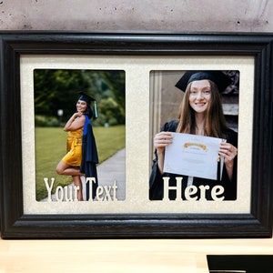 May include: Black double photo frame with a beige mat. The frame has two openings, each with a graduation photo. The left photo shows a person in a yellow dress and blue graduation gown. The right photo shows a person in a black graduation gown holding a diploma. The text "Your Text" is below the left photo and "Here" is below the right photo.
