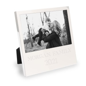 Puede incluir: Un marco de fotos plateado con un soporte negro. El marco tiene una foto en blanco y negro de una mujer sosteniendo a un niño. El texto "MORGAN FAMILY 2021" está grabado en el marco.