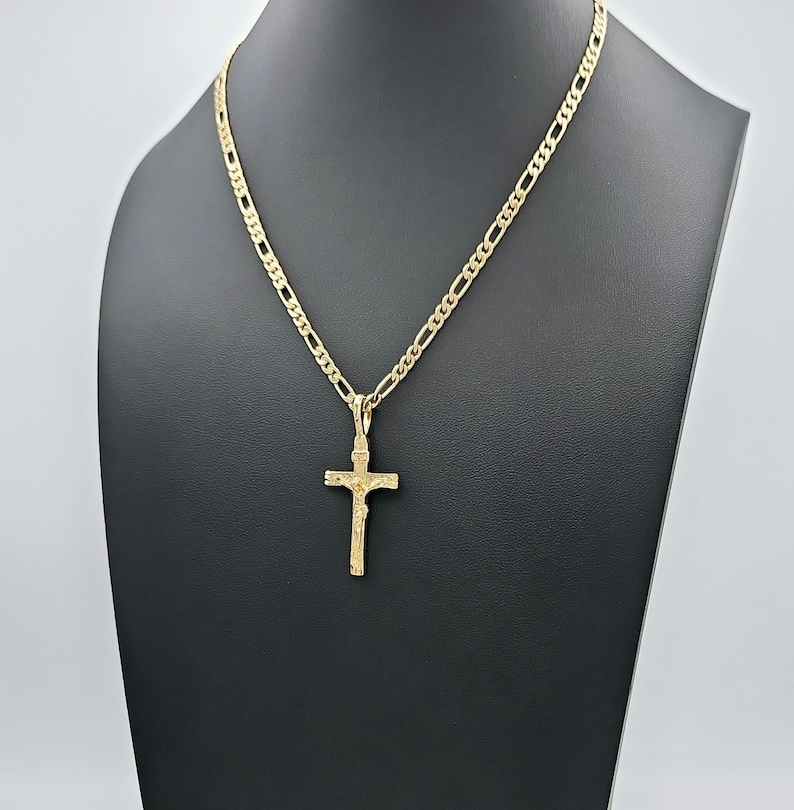 Puede incluir: Un collar de cadena de oro con un colgante de cruz de oro. La cadena es de estilo eslab&oacute;n cubano.